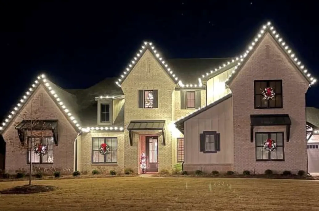 Roofline lights and window wreaths on a two-story brick and board-and-batten home.